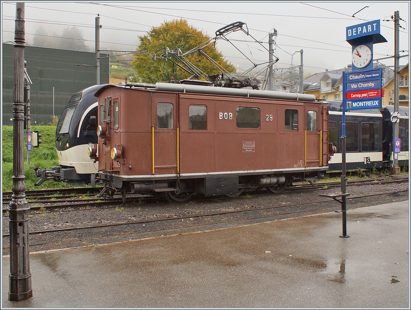La DER de la Saison / Das Saison Ende der Blonay Chamby Bahn 2025 - Seit einigen Jahren zeigt die Blonay Chamby Bahn zum Saison Ende mit einem verdichteten Fahrplan noch einmal ihre herrlichen Fahrzeuge im Einsatz: Die BOB HGe 3/3 29 der Blonay - Chamby Bahn wartet in Blonay auf ihre Komposition; die Zugzielanzeige für den nächsten Zug nach Chamby (mit Anschluss nach Montreux) gilt aber nicht der BOB HGe 3/3 29 sondern dem (hier nicht zu sehenden) Dm 2/2  Biniou  der Blonay - Chamby Bahn auf Gleis 1 in Blonay.

25. Oktober 2025