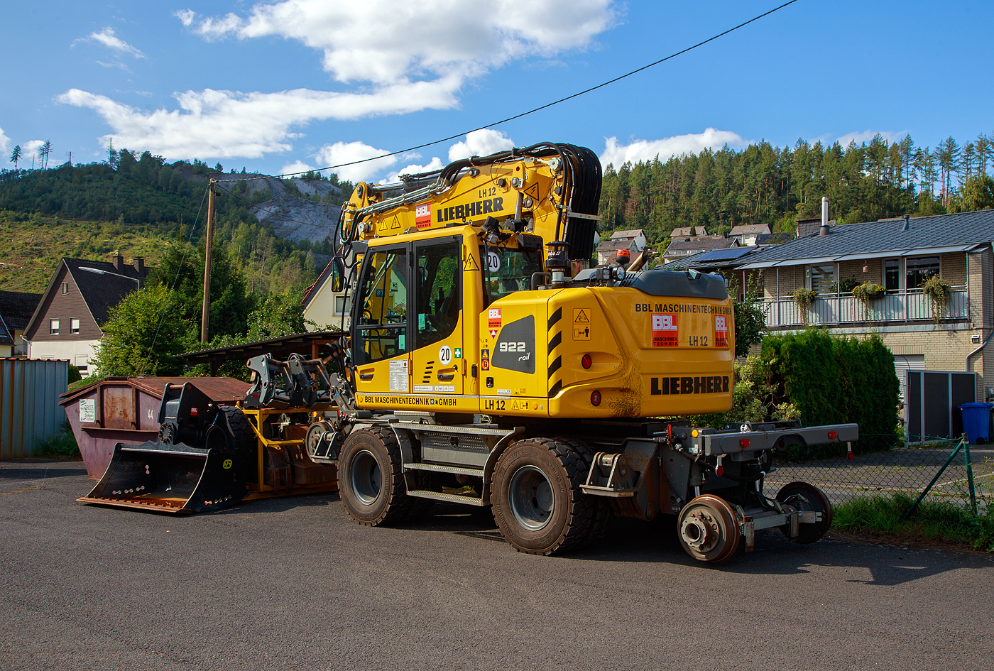 Liebherr Zweiwegebagger A 922 Rail Litronic (Baureihe 1190) mit Abstützpratzen, interne Nr. LH 12 der BBL Maschinentechnik GmbH (Lüneburg), eigestellt durch die SES Aus- und Fortbildung e.K. (Horst / Holstein) unter der Kleinwagen Nr. D-SESAF 99 80 9904 303-1, abgestellt am 26.08.2023 in Herdorf (Ostweg) beim Lokschuppen der KSW, Betriebsstätte FGE -Freien Grunder Eisenbahn.

Der ZW-Bagger wurde 2022 von Liebherr unter der Fabriknummer KLHZ1509JZK137327 gebaut.

Der A 922 Rail Litronic kann als Zweiwegemaschine wahlweise auf der Straße oder auf Eisenbahnschienen eingesetzt werden. An beiden Seiten des Unterwagens ist das Schienenfahrwerk angebracht. Während des Aufgleisens bringt das Schienenfahrwerk die Bereifung auf Schienenniveau, wobei die inneren Räder der Zwillingsbereifung den Fahrantrieb auf der Schiene übernehmen.

TECHNISCHE DATEN:
Spurweite: 1.435 mm
Länge über Puffer: 6.400 mm
Achsabstand (Schiene): 5.700 mm
Laufraddurchmesser (Schiene): 500 mm (neu)
Eigengewicht: 24 t
Motorbauart: wassergekühlter 4Takt - 4-Zylinder-Reihendieselmotor mit Common-Rail-Einspritzsystem, Turbolader und Ladeluftkühlung
Motortyp: Liebherr D924 – FPT 
Motorhubraum: 4,5 Liter
Motorleistung: 120 kW / 163 PS
Höchstgeschwindigkeit (Hg): 19,9 km/h (in Kreuzungen und Weichen 10 km/h)
Zugkraft: 117 kN
Bremse: Kfz.-/SFE-Bremse und Wagonbremsanlage
Zul. Anhängelast: 120 t (ungebremst 40 t)
Zur Mitfahrt zugel. Personenzahl: 1 (und Fahrer)
Antrieb auf Schiene: Über Reibantrieb der Straßenreifen
Hinterer Schwenkradius: 2.000 mm
Max. Neigung: 40 ‰
Max. Gleisüberhöhung: 200 mm
