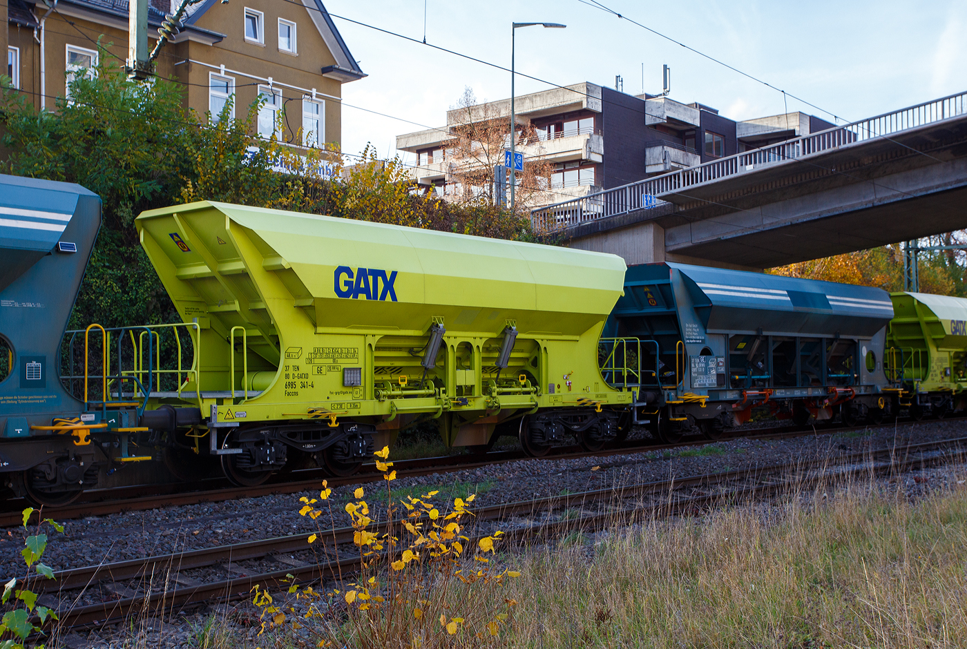 Recht neuer, vierachsiger offener Drehgestell-Schüttgutwagen mit Schwerkraft Entladung (Selbstentladewagen), 37 80 6985 341-4 D-GATXD, der Gattung Faccns (GATX Typ 8548) der GATX Rail Germany GmbH, am 04 November 2025 eingereiht im Zugverband bei einer Zugdurchfahrt im Bahnhof Kirchen/Sieg.

Der 4-achsige Wagen der Gattung Faccns mit einem G1 Lichtraumprofil und reduzierter Länge wird für den Transport von Schüttgütern mit einer Korngröße von min. 4mm (bzw. > 4mm), wie z.B. Kies, Splitt und Schotter eingesetzt. Die Auslaufschächte (Rutschen) können variabel eingestellt werden. So kann der Trichterinhalt sowohl neben den Schienen, als auch direkt zwischen den Schienen entladen werden. Die Entladung erfolgt per Schwerkraft, die Schieber werden über pneumatische Zylinder geöffnet. Die Neigung der Trichterwände beträgt 45°. Das Ladevolumen beträgt 48 m³.

ANMERKUNG:
Für eine flexible europaweite Einsetzbarkeit ist der Wagen für das Lichtraumprofil G1 ausgelegt. Der Wagen ist außerdem mit einem Zusatzluftbehälter ausgestattet, der eine autarke Betätigung der Entladeklappen ermöglicht. Darüber hinaus sind die Faccns-Wagen mit dem Kompaktbremssystem CFCB ausgestattet

TENISCHE DATEN:
Spurweite: 1.435 mm (Normalspur)
Länge über Puffer: 11.580 mm
Drehzapfenabstand: 6.780 mm
Achsabstand im Drehgestell: 1.800 mm
Laufraddurchmesser: 920 mm (neu)
Äußere Breite: 3.125 mm
Höhe über S.O.: 4.098
Laderaum: 48 m³
Beladeöffnung: 10.230 x 1.600 mm
Breite der Entladeschurren: 700 mm
Höhe der Schurre über S.O.: 680 mm
Entladeklappen: 4
Entladesystem: pneumatisch
Höchstgeschwindigkeit: 100 km/h (beladen) / 120 km/h (leer)
Eigengewicht: 20.800 kg
Maximales Ladegewicht: 69,2 t (ab Streckenklasse D4)
Bauart der Bremse: KE-GP-A (K)
Bremssohle: C 810
Kleinster bef. Gleisbogenradius: R 35 m
Intern. Verwendungsfähigkeit: TEN-GE (G1)

