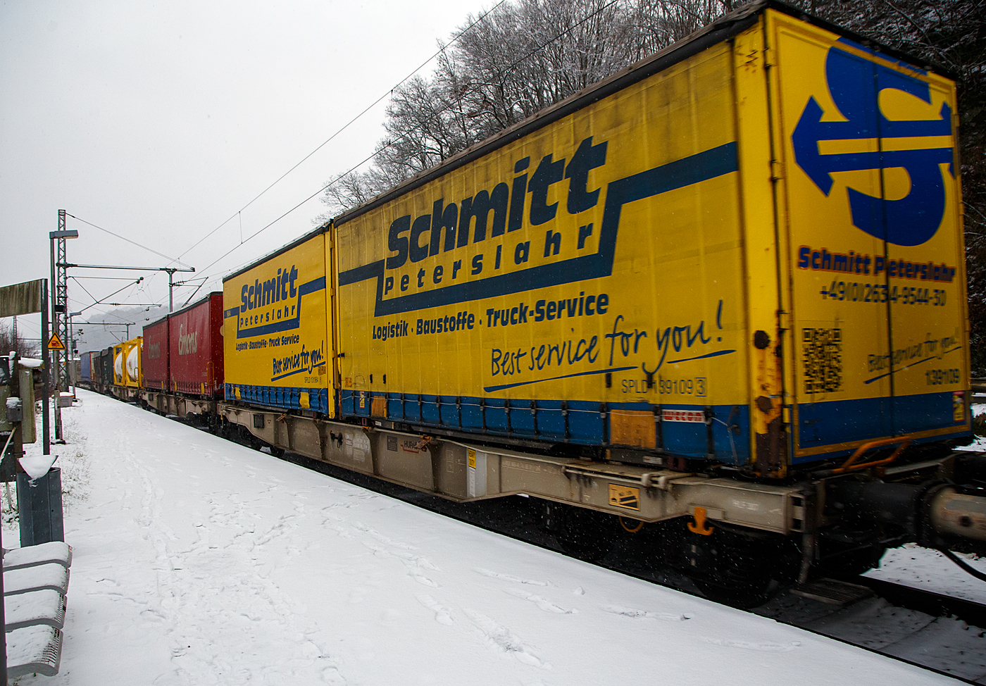 Vierachsiger Drehgestell-Containertragwagen der Gattung Sgmnss, 33 85 4578 226 CH-HUPAC, der HUPAC AG, beladen mit 2 Wechselbrücken, am 19.01.2023 im Zugverband bei der Durchfahrt in Scheuerfeld (Sieg) in Richtung Köln.

TECHNISCHE DATEN:
Hersteller: Ferriere Cattaneo SA (Schweiz)
Spurweite: 1.435 mm
Länge über Puffer: 17.340 mm
Drehzapfenabstand: 12.200 mm
Achsabstand in den Drehgestellen: 1.800 mm
Laufraddurchmesser: 920 mm (neu)
Ladelänge: 16.000 mm
Höhe der Ladeebene über S.O.: 1.115 mm
Eigengewicht: 16.500 kg
Max. Zuladung bei Lastgrenze S: 73,5 t (ab Streckenklasse D)
Max. Zuladung bei Lastgrenze SS: 63,5 t (ab Streckenklasse C)
Max. Geschwindigkeit: 100 km/h (Lastgrenze SS und leer 120 km/h)
Kleinster befahrbarer Gleisbogen: R 75 m
Bremse: KE-GP-A
Bremssohle: Jurid 816M
Feststellbremse: Ja
Verwendungsfähigkeit: TEN-GE

Die Bedeutung der Gattungs- und Kennbuchstaben (hier Sgmnss):
S - Drehgestellflachwagen in Sonderbauart
g - für den Transport von Containern mit einer Gesamtladelänge bis 60 Fuß eingerichtet
m - mit vier Radsätzen bei Ladelänge 15 m bis unter 18 m
n - mit vier Radsätzen höchste Lastgrenze über 60 t
ss - lauffähig bis 120 km/h (beladen)