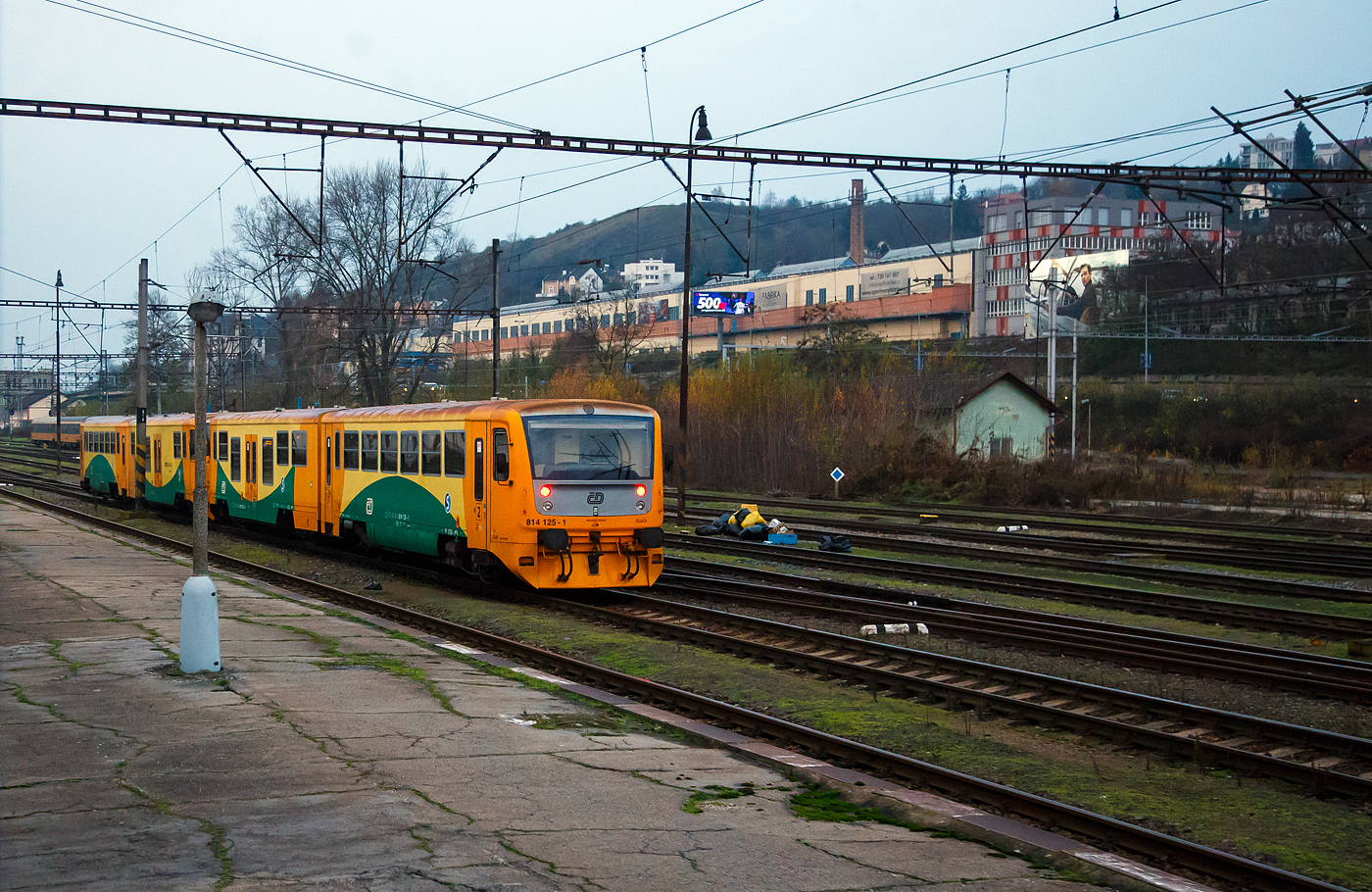 Wir überholen zwei gekuppelte Regionova (814 111/ 914 111 und 914 125/814 125) der České dráhy (ČD) am 24.11.2022 bei Praha-Smichov. Aufnahme aus dem Zugheraus.

Die Fahrzeuge der ČD-Baureihe 814/914 entstanden im Rahmen eines Rekonstruktionsprogrammes (2005 bis 2012) aus den Fahrzeugen der ČD-Baureihe 810,ex ČSD M 152.0  Chcípák  (Brotbüchse). Von den ČD werden sie als „Regionova“ vermarktet.