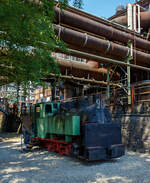 Die 785 mm Schmalspur-Dampflokomotive Nr. 20 der Völklinger Hütte (ehem. Röchling'schen Eisen- und Stahlwerke GmbH in Völklingen/Saar, ab 1982 ARBED-Saarstahl GmbH, ab 1986 Saarstahl Völklingen GmbH) hier am 01 Juli 2025 abgestellt, mit dem Schlackewagen 127 (mit Kübel ARBED 219), als Denkmal beim Biergarten Völklinger Hütte. Heutiger Eigentümer ist die Initiative Völklinger Hütte e.V..

Die Dampflok vom Typ Krauss XXXII kk wurde 1904 von Krauss & Comp. in München unter der Fabriknummer 5168 gebaut und an die RESW - Röchling'sche Eisen- und Stahlwerke AG in Völklingen geliefert und dort als Lok  21  in den Bestand eingereiht. Später tauschte sie mit ihrer Schwesterlok 20 die Betriebsnummer und wurde fortan als Lok  20  eingesetzt. 1978 erfolgte die Aufstellung auf einem Spielplatz in Völklingen-Ludweiler. Im Oktober 1990 übernahm Carreau Wendel vom Musée du bassin houllier Lorrain im französischen Moselle die Lok als Ausstellungsstück. Von dort konnte sie 1997 nach Völklingen zurück und nach einer äußerlichen Aufarbeitung 1998 von der Initiative Völklinger Hütte e.V. in der Alten Völklinger Hütte aufgestellt werden.

Auf dem ehemals 20,4 km langen Schmalspurnetz der Hütte (Spurweite 785 mm) verrichteten bis zu 17 Dampflokomotiven ihren Dienst. Auf der Stahlwerksseite transportierten sie die Schlacke zur Thomasmühle. Die Unterführungen 2 und 3 dienten dem Transport von Stahlblöcken und allgemeinen Gütern zur Versorgung des Walzwerks auf der Eisenwerkseite und dem Abtransport der Walzprodukte. Im Hochofenbereich wurde die Abfuhr der Hochofenschlacke zur Schlackenbrechanlage auf der anderen Saarseite durchgeführt.

Wegen des neuen Stahlwerks, das im Dezember 1980 in Betrieb ging, waren umfangreiche Umbaumaßnahmen notwendig. Der Roheisenkanal wurde tiefer gelegt, die Verbindung zum alten Stahlwerk unterbrochen und im Bereich des Hochofens 6 musste ein neuer Gleisanschluss hergestellt werden. Dadurch musste für die schmalspurige Schlackenbahn eine Hubbrücke gebaut werden, da sich Schmalspurgleis und Roheisengleis auf unterschiedlichem Niveau befinden.

Die baugleiche Lokomotive 21 ist auch vorhanden, sie steht mit zwei Schlackenwagen am Ausgang des Schlackenkanals auf der abgesenkten Hubbrücke in Richtung Schlackenbrechanlage. Leider konnte ich diese nicht entdecken.

TECHNISCHE DATEN der Lok 20 und 21 
Hersteller: Krauss & Comp., München
Typ: XXXII kk
Baujahr: 1904
Spurweite: 785 mm (Schmalspur)
Achsfolge: B
Länge: 5.400 mm
Achsabstand: 1.400 mm
Triebraddurchmesser: 680 mm (neu)
Breite: 1.800 mm
Höhe: 2.650 mm
Dienstgewicht: 16 t
Höchstgeschwindigkeit: k. A. 
Leistung: 80 PS
Zugkraft: 3 t
Zylinder: 2 Stück, Ø 260 mm x 380 mm Hub
Dampfdruck: 14 bar
Heizfläche: 20,62 m²
Rostfläche: 0,43 m“
Anzahl Siederohre: 80 Stück
Durchmesser Siederohre: 39/42 mm
Länge Siederohre: 2.510 mm
Wasservorrat: 1.400 l (1,4 m³)
Kohlenvorrat: 300 kg