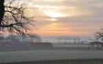 Die 146 223-3 kommt mit einem Doppelstockzug aus Augsburg durch den Frühdunst bei Sonnenaufgang in Neu-Ulm Pfuhl durch, am 21.11.2009.