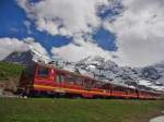 Vor dem Massiv des 3970 m hohen Eigers mit der wolkenverhangenen Spitze der Eigernordwand und des 4107 m hohen Mönchs befindet sich der 2002 in Betrieb genommene Triebwagen 218 kurz vor der