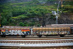 Zweiachsiger, großräumiger Schiebewandwagen 21 85 2457 475-1 CH-SBBC, der Gattung Hbbillns, der SBB Cargo AG, abgestellt am 02 August 2025 in Airolo. Das Bild entstand aus einem Zug heraus.

Der Güterwagen ist ein gedeckter zweiachsiger Schiebewandwagen mit fest verriegelbaren Trennwänden. Speziell geeignet für empfindliche Güter auf Paletten. Schützt vor Nässe und Transporteinwirkungen.

Die Be- und Entladung erfolgt seitlich, ca. die ½ Seite lässt sich öffnen. Das max. Ladegewicht beträgt 28,5 t (38 Paletten)

TECHNISCHE DATEN:
Spurweite: 1.435 mm
Länge über Puffer: 16.720 mm
Achsabstand: 10.000 mm
Länge x Breite der Ladefläche: 13.700 x 2.900 mm
Eigengewicht: 19.500 kg
Ladefläche: 39,7 m²
Rauminhalt: 99,4 m³
Max. Ladegewicht: 21,0 t (ab Streckenklasse C) / 28,5 t (ab Streckenklasse D)
Höchstgeschwindigkeit: 100 km/h (beladen) / 120 km/h (leer)
Bremse: KE-GP-A (K)
Bremssohle: Jurid 816M
Feststellbremse: Nein
Kleinster, befahrbarer Gleisradius: R 35 m
Intern. Verwendungsfähigkeit: RIV

Die Bedeutung der Gattungs- und Kennbuchstaben (hier Hbbillns):
H - Gedeckter Wagen in Sonderbauart
bb - Ladelänge 14 m und mehr
i - Schiebewände
ll - Verriegelbare/bewegliche Trennwände
s - Höchstgeschwindigkeit 100 km/h (beladen)
